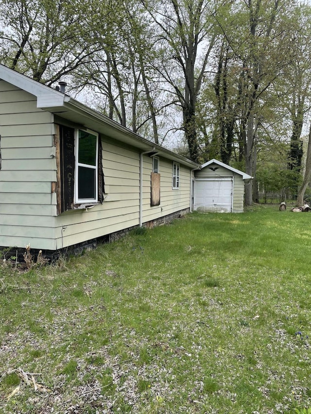 view of home's exterior featuring a detached garage, an outdoor structure, and a yard