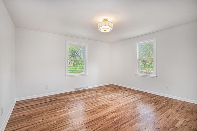 unfurnished room with baseboards, visible vents, and light wood-type flooring