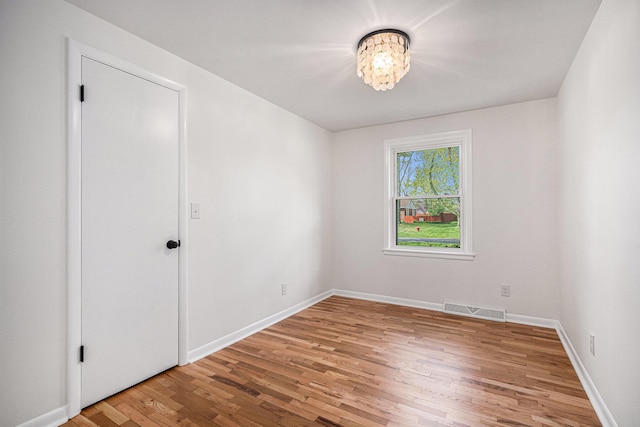 unfurnished room featuring visible vents, baseboards, a notable chandelier, and light wood-type flooring