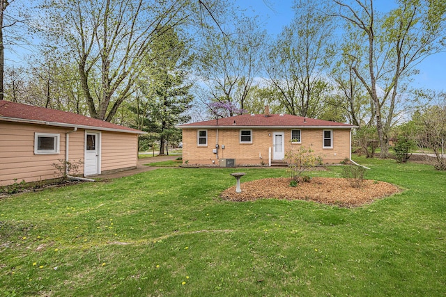 rear view of house with a lawn, brick siding, and central air condition unit