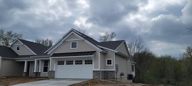 craftsman house featuring board and batten siding, a standing seam roof, a garage, concrete driveway, and stone siding