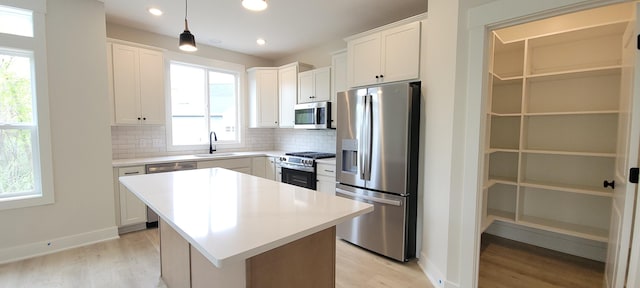 kitchen featuring appliances with stainless steel finishes, decorative backsplash, and light wood-style flooring
