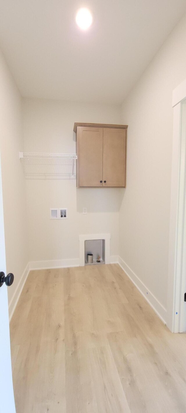 washroom featuring light wood-style floors, hookup for a washing machine, cabinet space, and baseboards