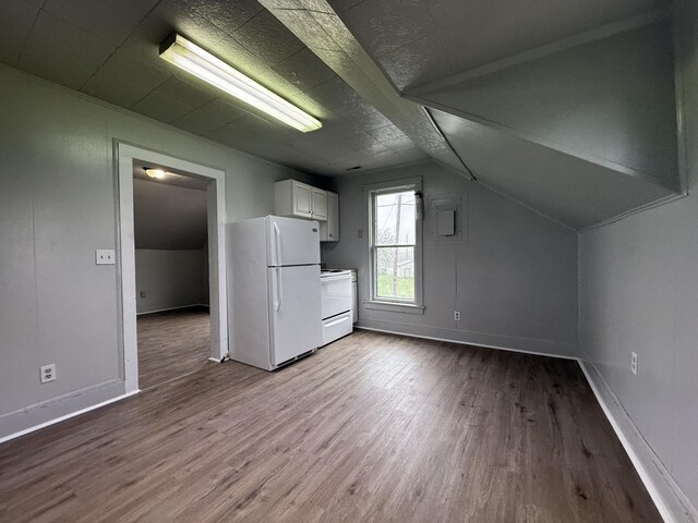 additional living space with dark wood-type flooring, baseboards, and vaulted ceiling