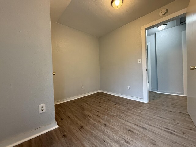 empty room with baseboards, wood finished floors, and lofted ceiling