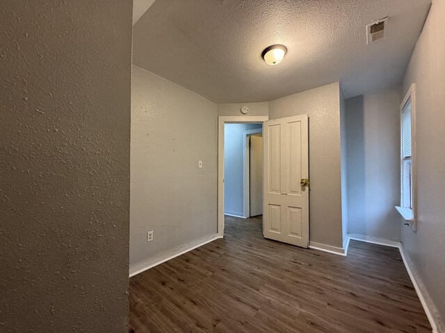 spare room featuring visible vents, baseboards, a textured ceiling, and wood finished floors