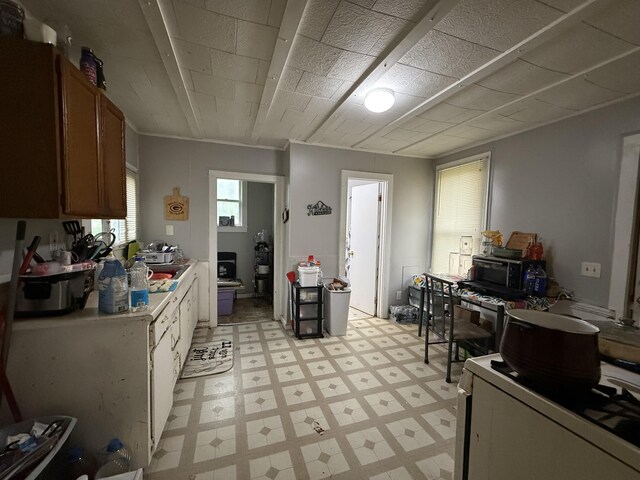 kitchen featuring light countertops, light floors, brown cabinetry, and a sink