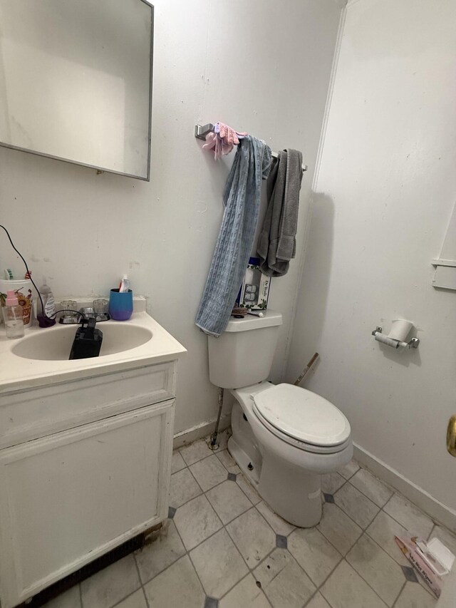 half bathroom with vanity, tile patterned flooring, and toilet