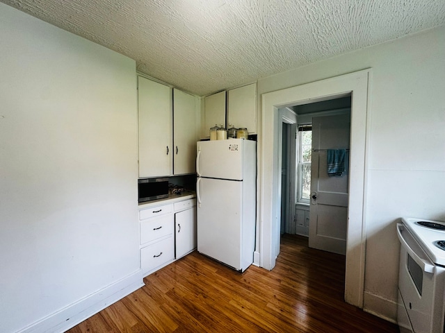 kitchen with white appliances, dark wood finished floors, and white cabinets