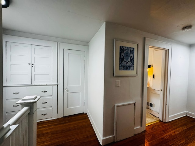 hallway with baseboards, dark wood finished floors, and visible vents