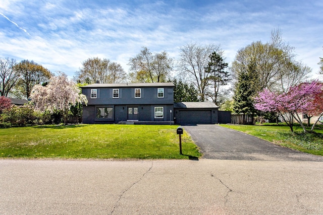 colonial home featuring a garage, fence, a front lawn, and aphalt driveway