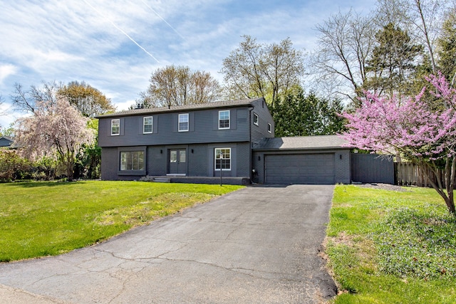 colonial home featuring fence, an attached garage, a front lawn, brick siding, and driveway
