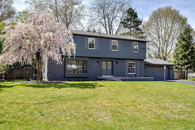 colonial inspired home featuring fence, driveway, a front yard, and a garage
