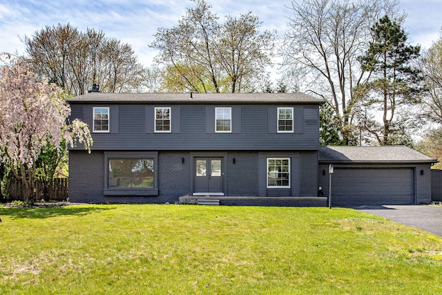colonial home featuring a garage, driveway, a front yard, and entry steps