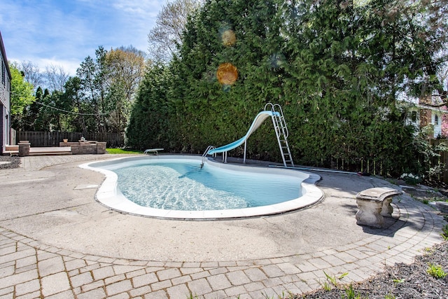 outdoor pool with fence, a water slide, and a patio area
