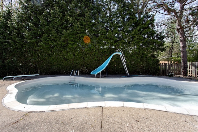 view of swimming pool featuring fence, a fenced in pool, and a water slide