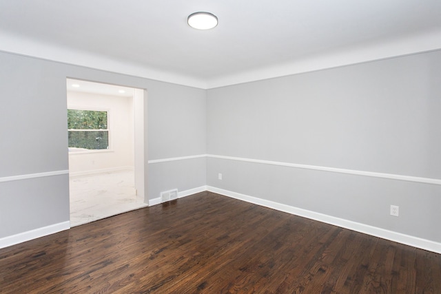 spare room featuring baseboards, visible vents, and dark wood-style floors