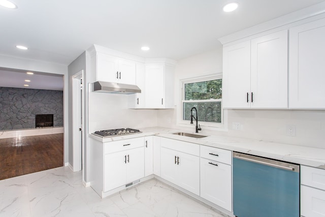 kitchen with a sink, under cabinet range hood, marble finish floor, and dishwasher