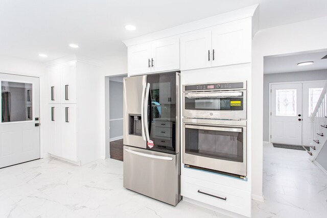 kitchen featuring white cabinets, appliances with stainless steel finishes, marble finish floor, recessed lighting, and baseboards