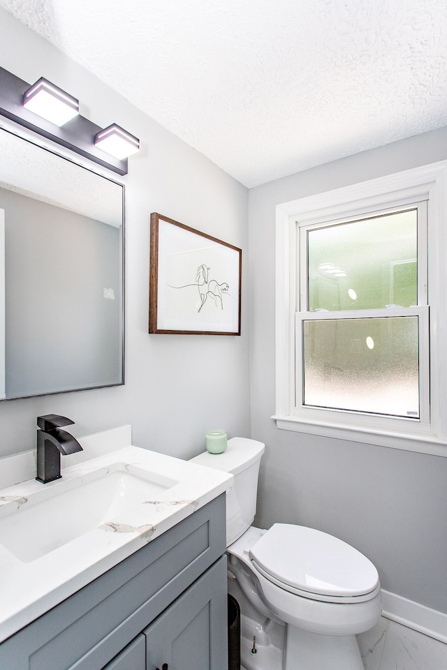 half bath featuring toilet, a textured ceiling, marble finish floor, and vanity