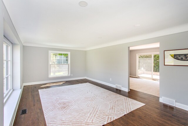 spare room with dark wood-style flooring, visible vents, and a wealth of natural light
