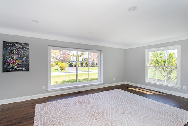 unfurnished room featuring baseboards, dark wood finished floors, and visible vents