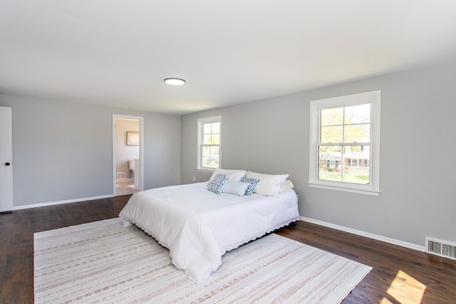 bedroom with visible vents, baseboards, ensuite bathroom, and wood finished floors