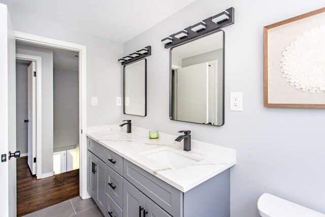 full bathroom with double vanity, toilet, tile patterned floors, and a sink