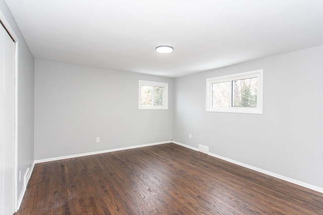 spare room featuring baseboards and dark wood-style floors