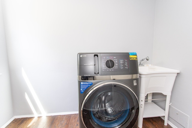 laundry room featuring visible vents, laundry area, wood finished floors, baseboards, and washer / clothes dryer