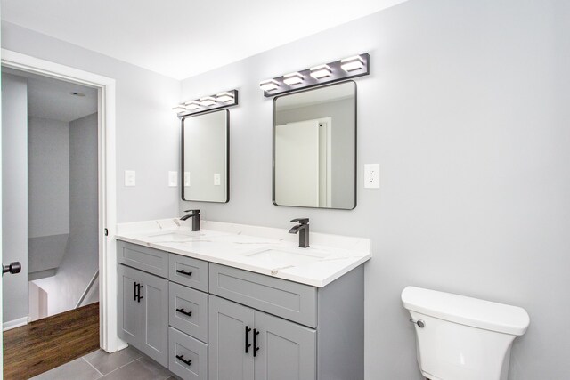 bathroom with double vanity, toilet, a sink, and tile patterned flooring