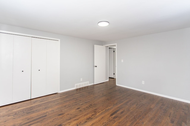 unfurnished bedroom featuring baseboards, dark wood-style floors, and visible vents