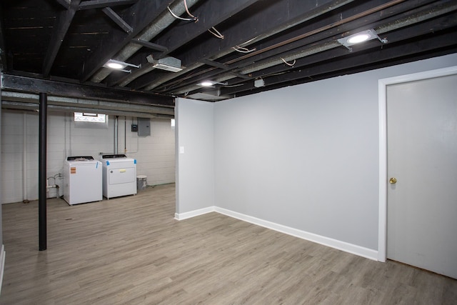below grade area with baseboards, electric panel, wood finished floors, and washer and dryer