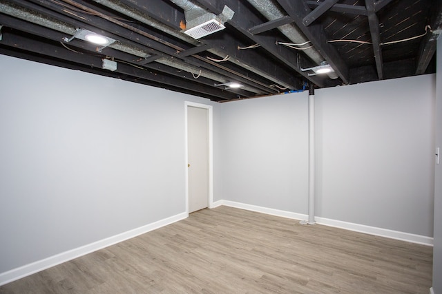 finished below grade area featuring baseboards, visible vents, and wood finished floors