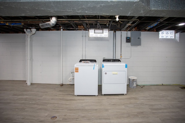 washroom with electric panel, laundry area, wood finished floors, and washer and dryer