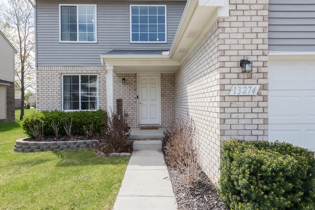 doorway to property with a lawn, brick siding, and a garage