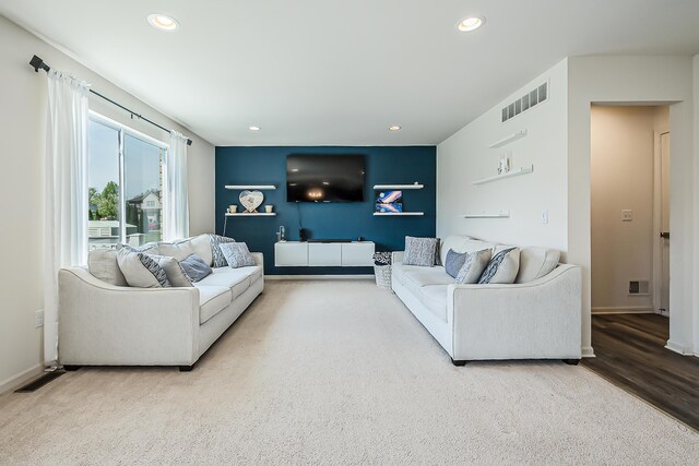 carpeted living room featuring baseboards, recessed lighting, wood finished floors, and visible vents