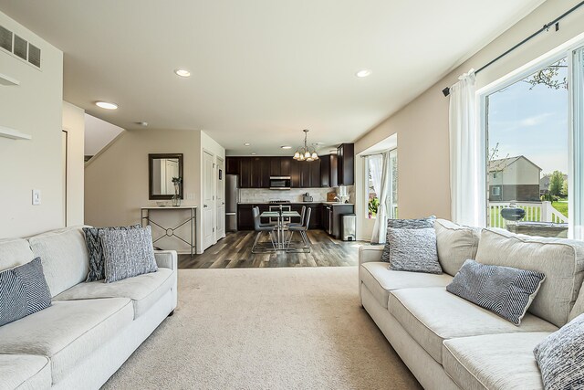 living room featuring recessed lighting, plenty of natural light, dark wood-style flooring, and a chandelier