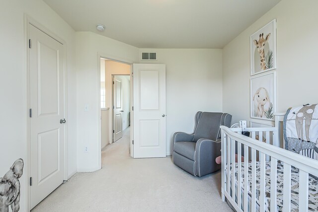 bedroom featuring a nursery area, light carpet, and visible vents