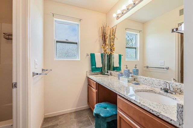 full bath featuring double vanity, baseboards, visible vents, and a sink