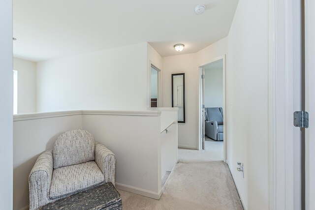 corridor featuring light colored carpet and baseboards