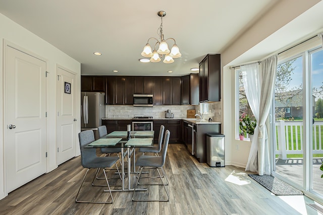 dining area with baseboards, recessed lighting, wood finished floors, and a chandelier