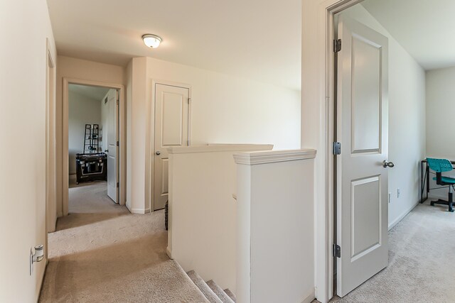 hall with baseboards, light carpet, and an upstairs landing