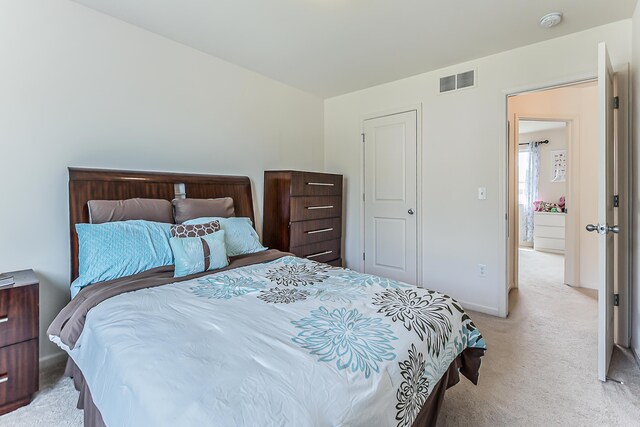 bedroom with baseboards, visible vents, and light carpet