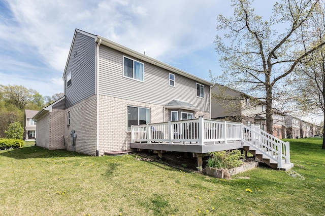 rear view of property with brick siding, a lawn, and a deck