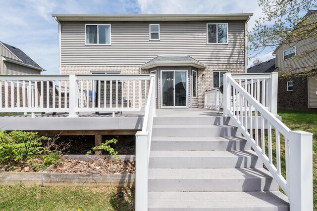 back of house featuring stairs, brick siding, and a deck