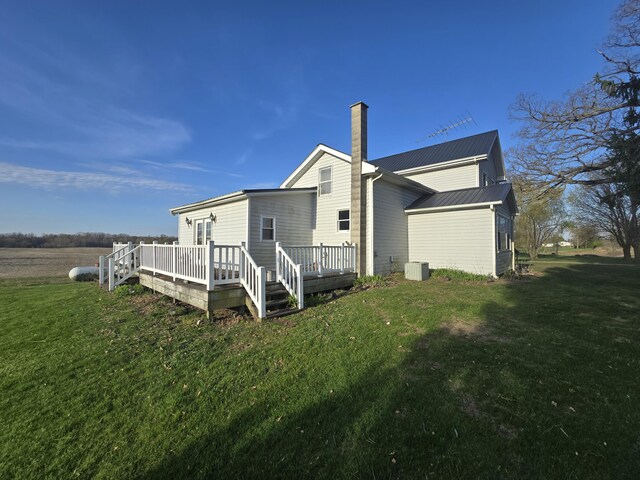 back of house with a deck, a chimney, metal roof, central air condition unit, and a yard