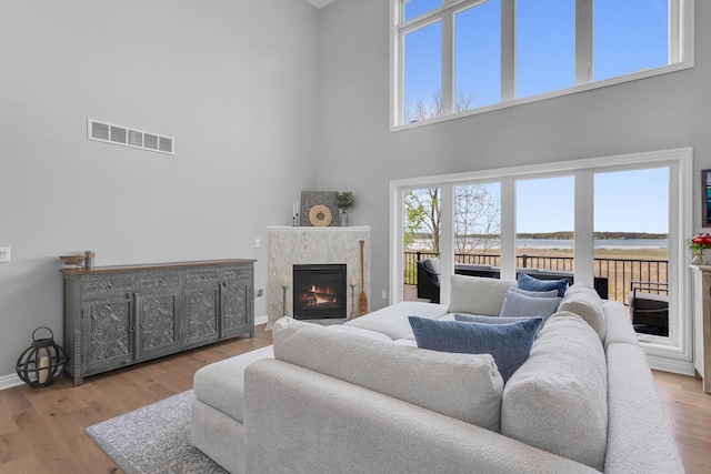 146 Bloomfield Blvd, Brooklyn, MI 49230 - living room featuring visible vents, a towering ceiling, a fireplace, wood finished floors, and baseboards