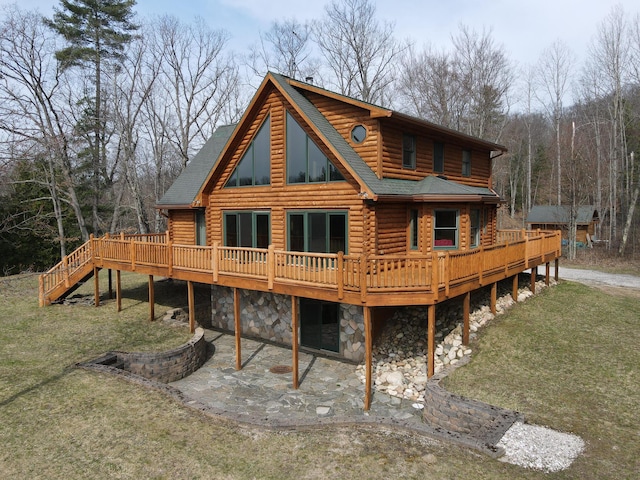 back of house with a lawn, log exterior, a patio area, and a deck
