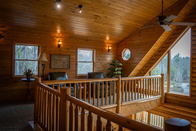 stairs with wooden ceiling, a ceiling fan, vaulted ceiling, and wood walls